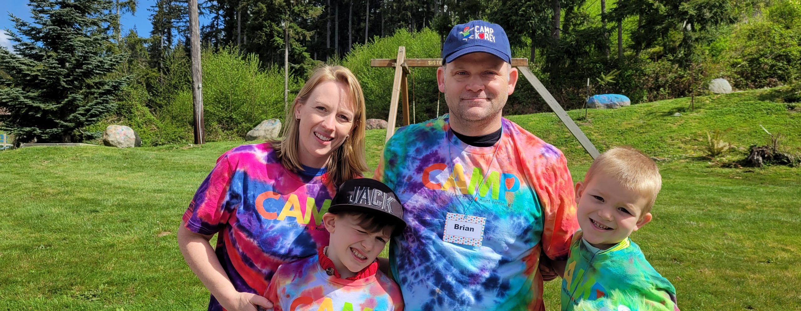 two campers stand with their parents wearing tie dye shirts they made at camp
